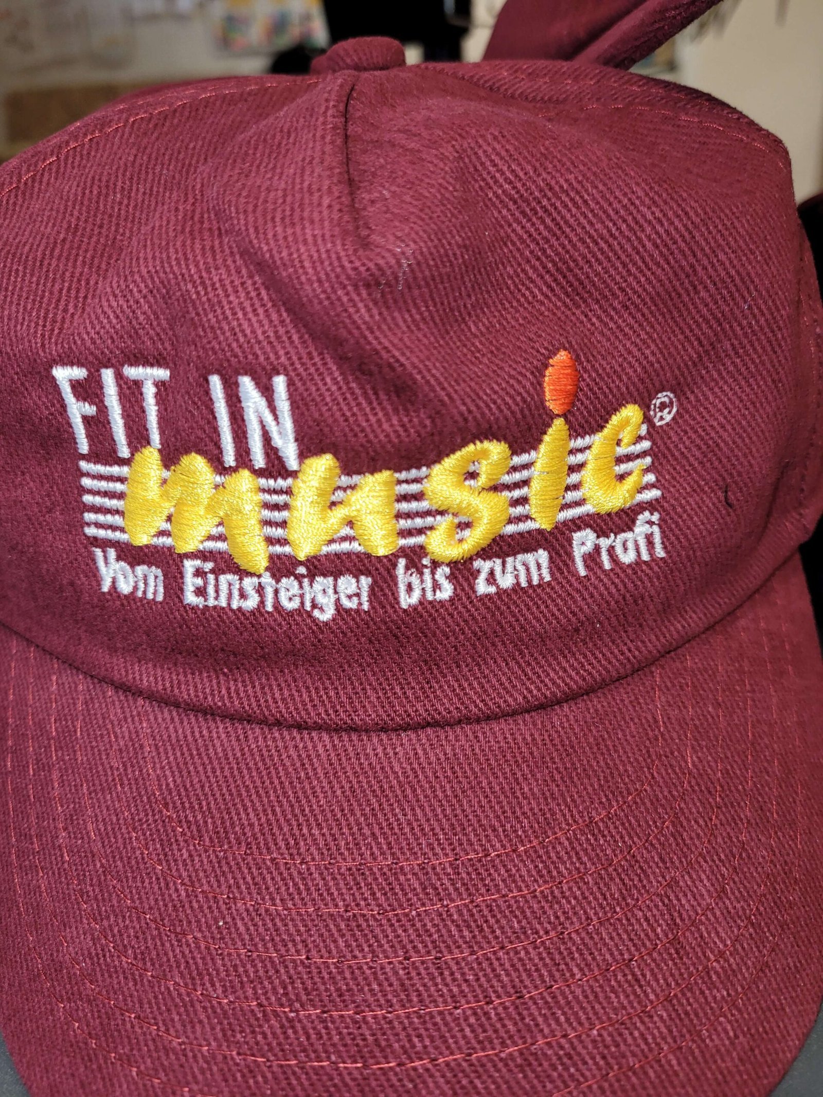 Nahaufnahme einer bordeauxroten Cap mit weiß-gelber Stickerei