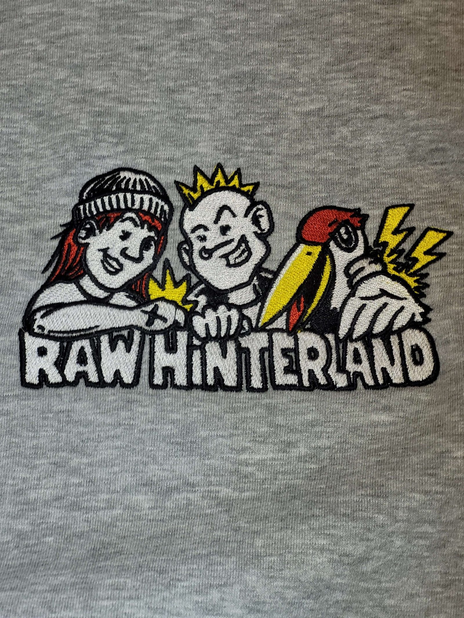 Mehrfarbige Stickerei mit Comicfiguren auf grauem Sweatstoff